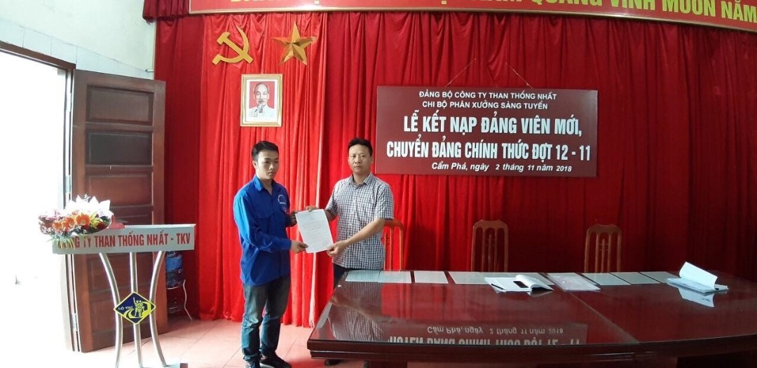 Đồng chí Trần Quang Cường - Bí thư Chi bộ Phân xưởng Sàng tuyển trao Quyết định kết nạp đảng viên mới cho quần chúng ưu tú Nguyễn Đức Cảnh.